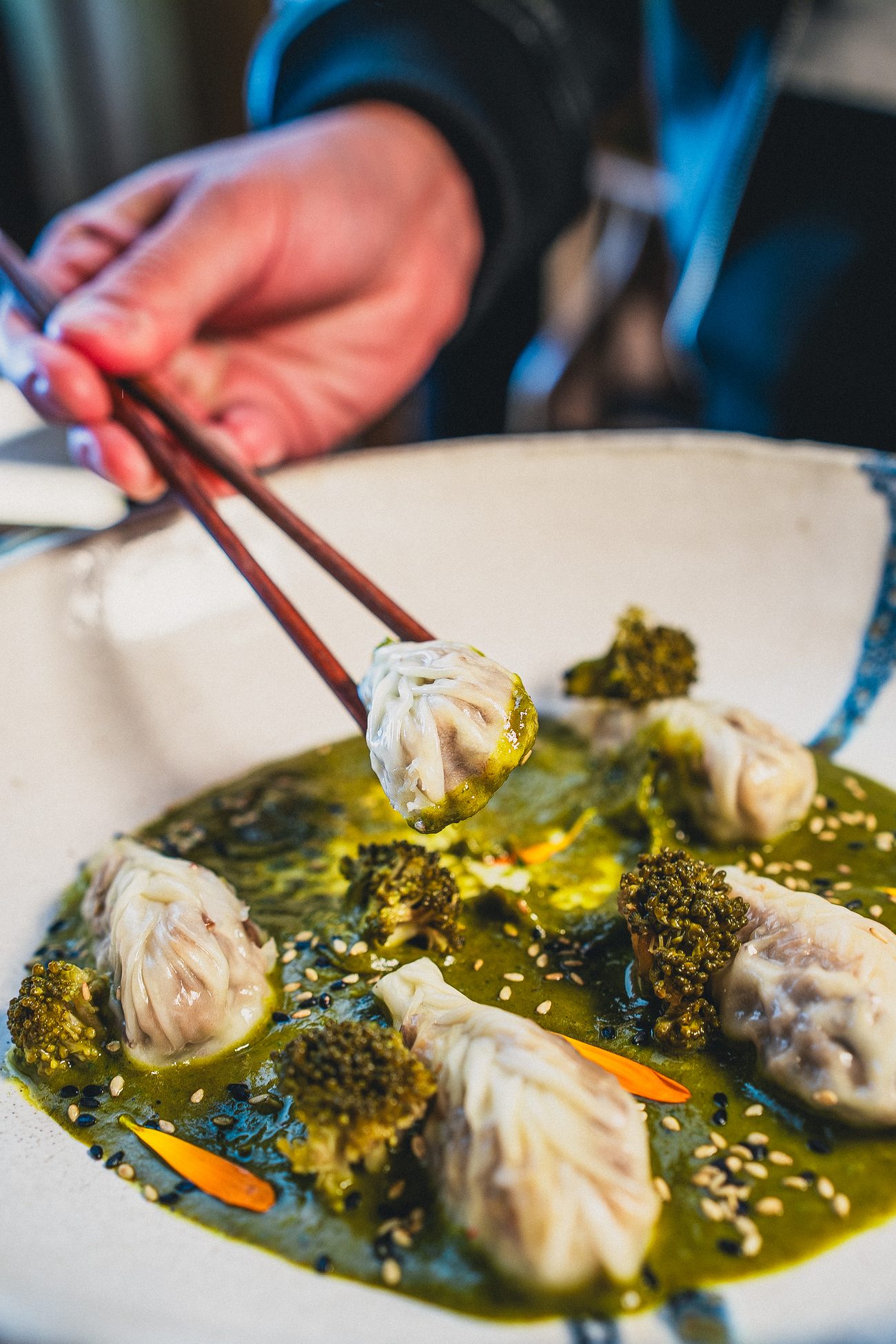 Dim sum de Kanpai sobre salsa verde con brócoli y sésamo